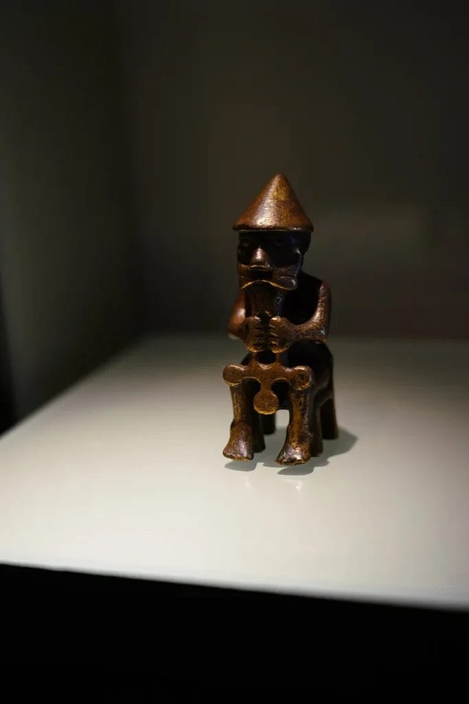 Small seated bronze figure with a short object held to the chest, often identified as Thor with a hammer.