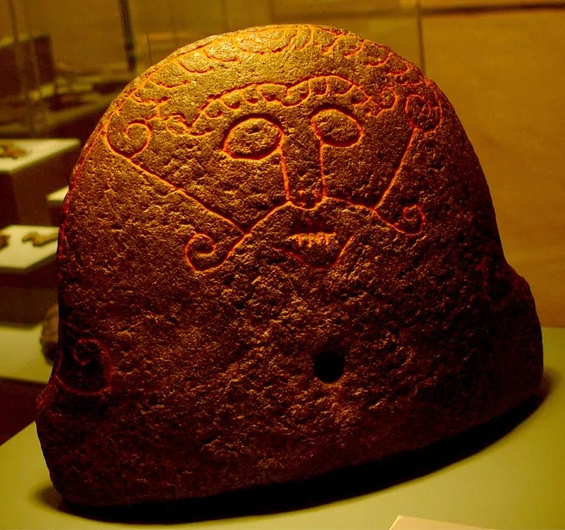 Soapstone hearth stone with a scratched face, lips sewn shut—often identified as Loki.