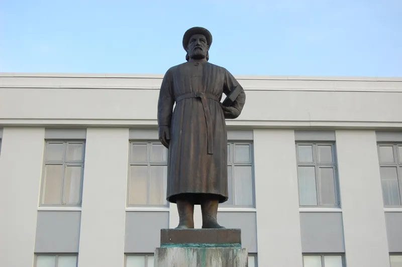 Statue of Snorri Sturluson at Reykholt, Iceland: a cloaked figure seated with a book, set against turf and stone.