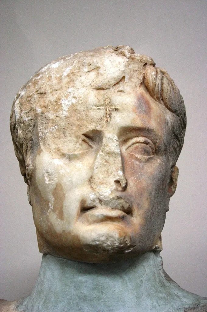 Marble bust of Augustus with the nose removed and a cross carved on the forehead.