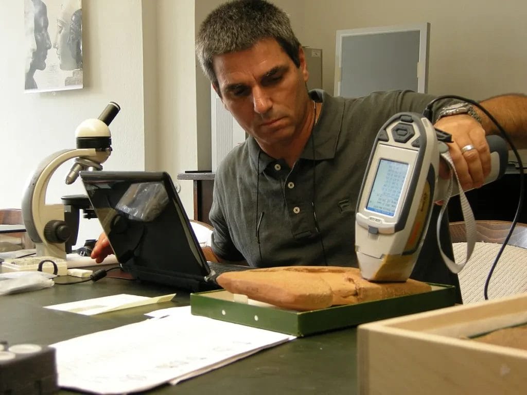 Researcher using a handheld XRF on cuneiform tablets
