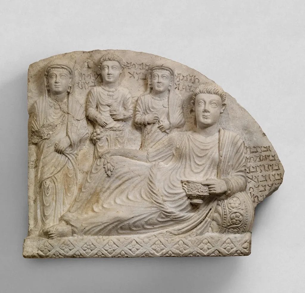 Stone relief carving showing reclining man at banquet with family members and inscriptions