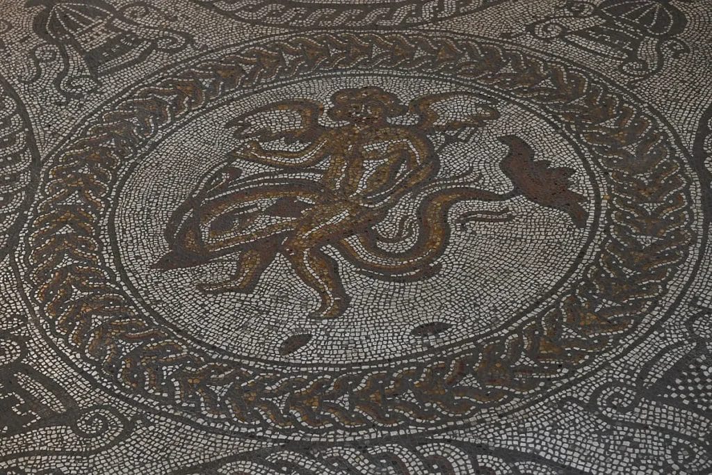 Close view of Cupid riding a dolphin made from mixed stone and pottery tesserae