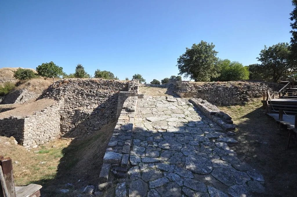 Stone fortification walls and terraces stand exposed on the mound of Hisarlik at the archaeological site identified with ancient Troy
